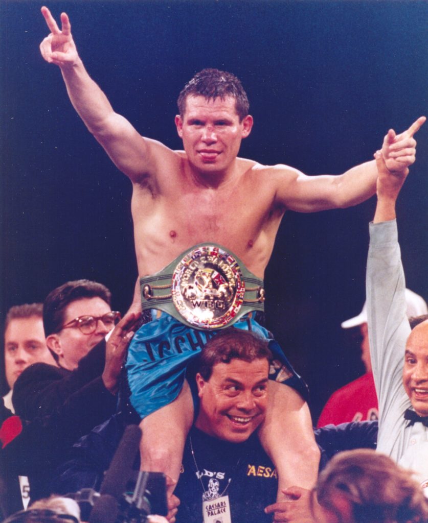 Boxer Julio Cesar Chavez is held aloft by another man and Chavez holds up his hands in a sign of victory.