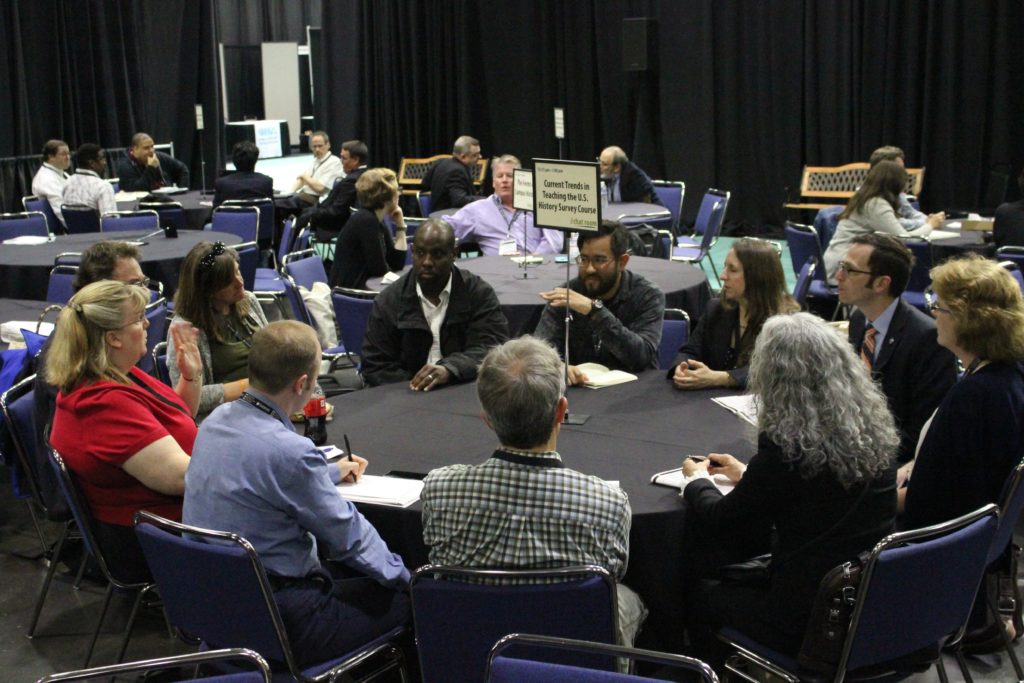 Several people sit around a round table and engage in conversation.