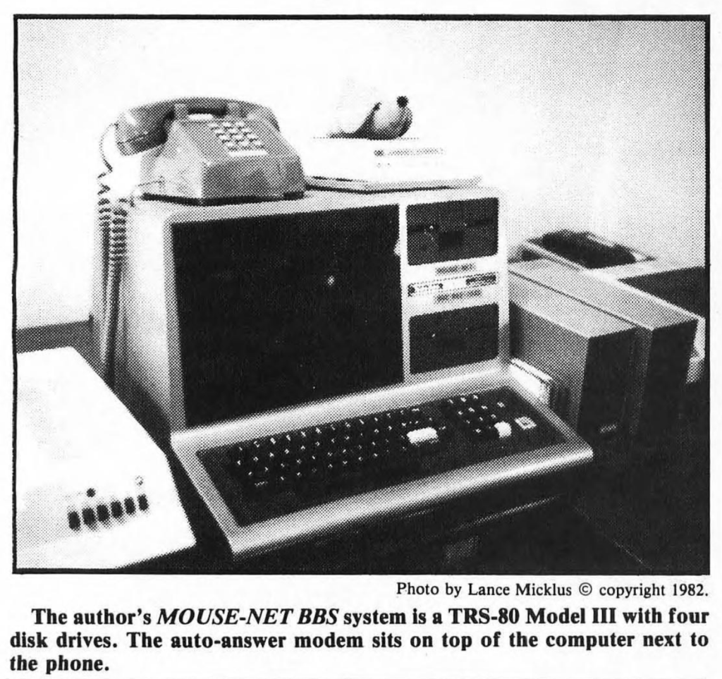 Black and white photograph of BBS system, including the caption: The Author's MOUSE-NET BBS System is a TRS-80 MOdel III with four disk drives. The Auto modem sits on top of the computer next to the phone."