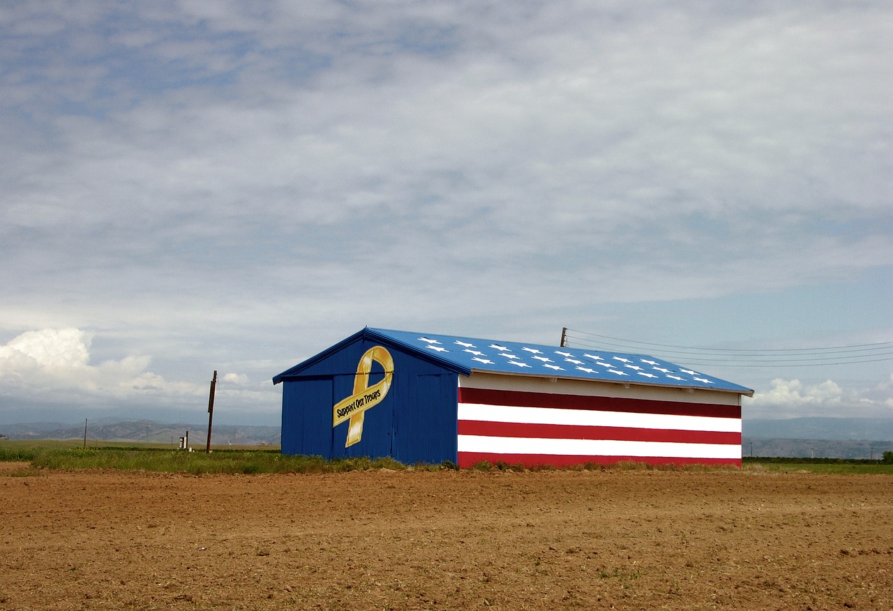A barn in a field painted with a yellow ribbon that reads "Support Our Troops."
